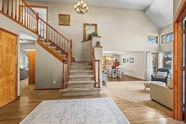 stairway featuring an inviting chandelier, wood-type flooring, and high vaulted ceiling