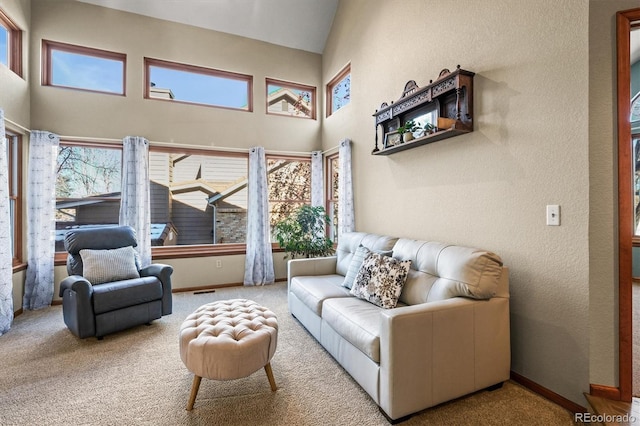 carpeted living area with a towering ceiling and baseboards