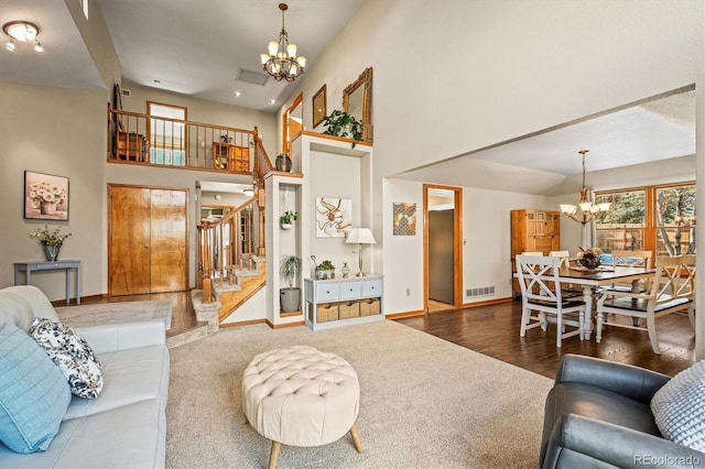 living room with stairs, a high ceiling, visible vents, and an inviting chandelier