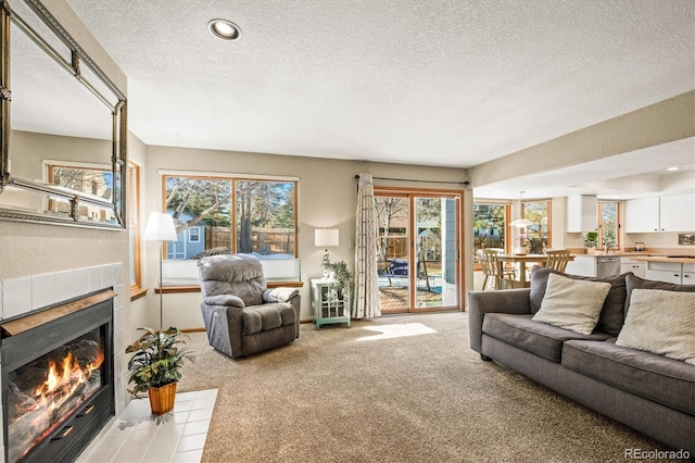 carpeted living room with a tiled fireplace and a textured ceiling