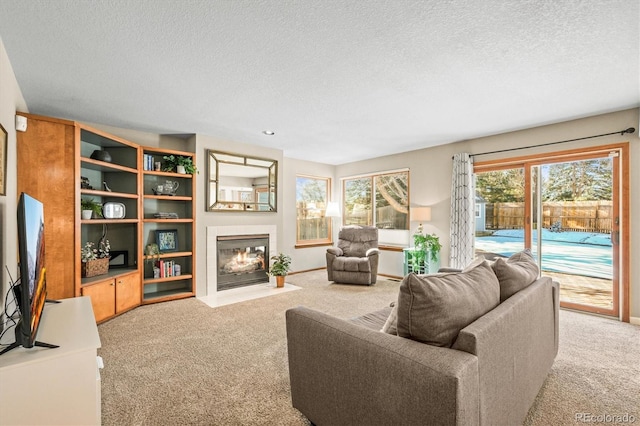 living room with a textured ceiling, a fireplace, carpet flooring, and baseboards