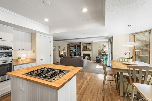 kitchen featuring butcher block countertops, a tray ceiling, stainless steel appliances, and white cabinetry