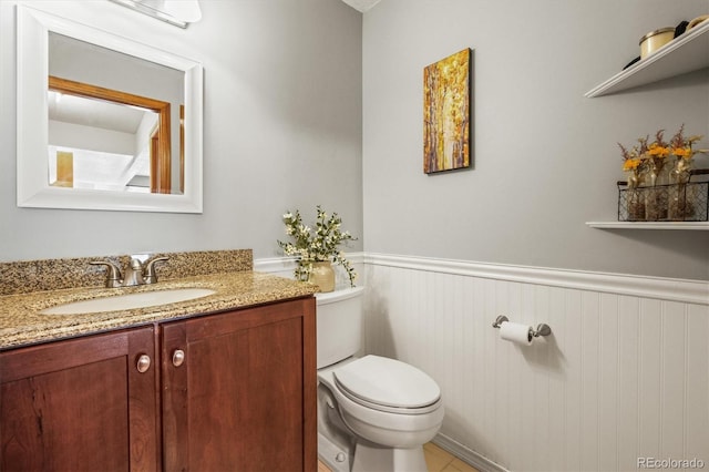 bathroom featuring toilet, a wainscoted wall, and vanity