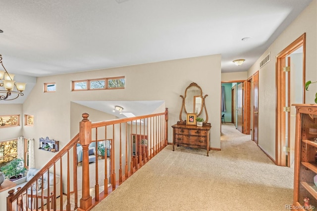 corridor with carpet floors, a notable chandelier, visible vents, an upstairs landing, and baseboards