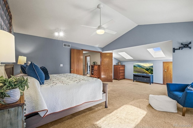 bedroom with ceiling fan, lofted ceiling with skylight, carpet flooring, and visible vents