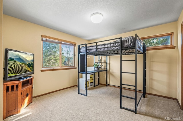 carpeted bedroom with a textured ceiling, multiple windows, and baseboards