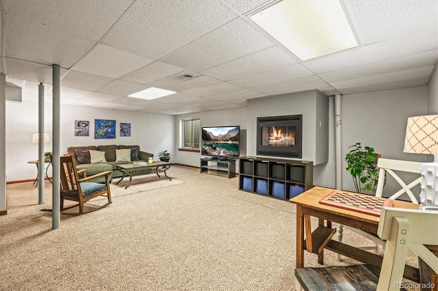 living area with baseboards, a drop ceiling, and carpet flooring