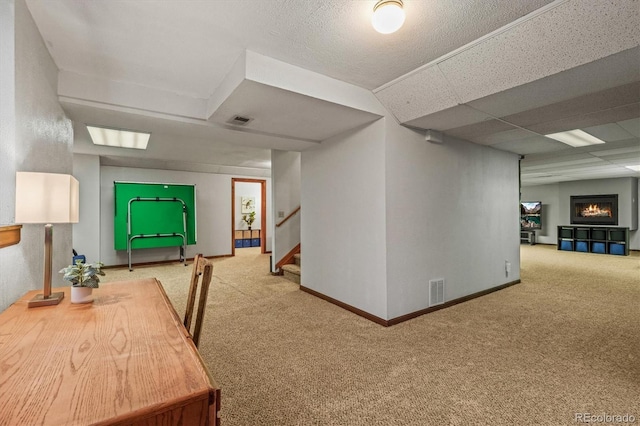 interior space with a paneled ceiling, baseboards, a fireplace, and visible vents