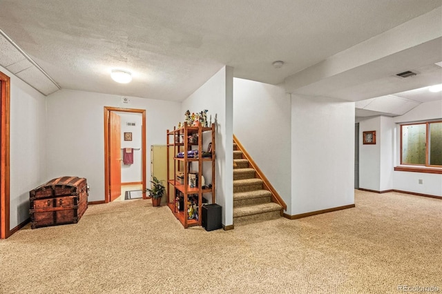 below grade area featuring visible vents, carpet flooring, a textured ceiling, baseboards, and stairs