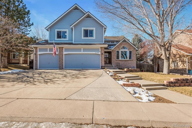 view of front facade with a garage, brick siding, driveway, and fence