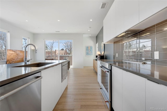 1300 N Ogden St Unit 304, Denver, CO 80218 - kitchen with stainless steel appliances, a sink, light wood-style flooring, white cabinets, and recessed lighting