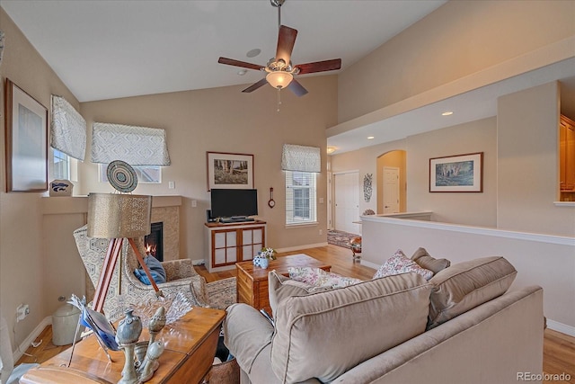 22124 E Euclid Dr, Aurora, CO 80016 - living room featuring a ceiling fan, a lit fireplace, light wood finished floors, arched walkways, and lofted ceiling