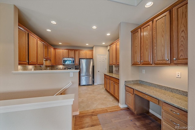22124 E Euclid Dr, Aurora, CO 80016 - kitchen featuring appliances with stainless steel finishes, built in study area, recessed lighting, light wood finished floors, and tasteful backsplash