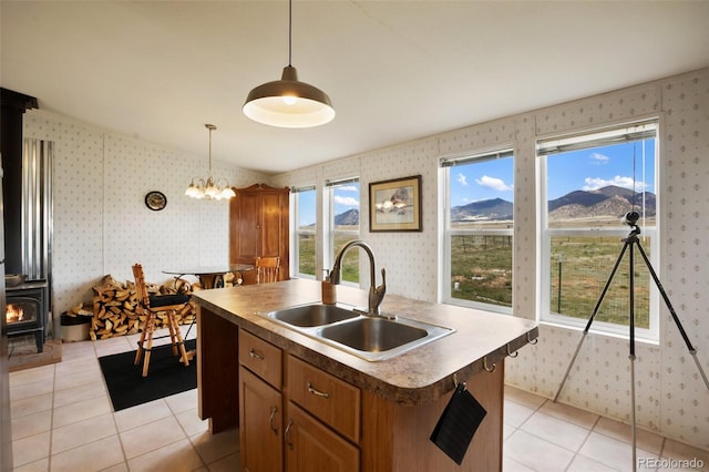 463 Snowshoe Ln, Lake George, CO 80827 - kitchen featuring a sink, a wood stove, wallpapered walls, brown cabinets, and light tile patterned floors