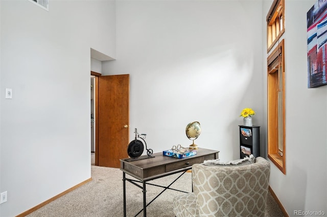 carpeted home office featuring a high ceiling