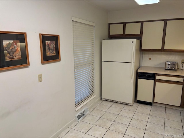 kitchen with visible vents, tasteful backsplash, freestanding refrigerator, light tile patterned flooring, and light countertops