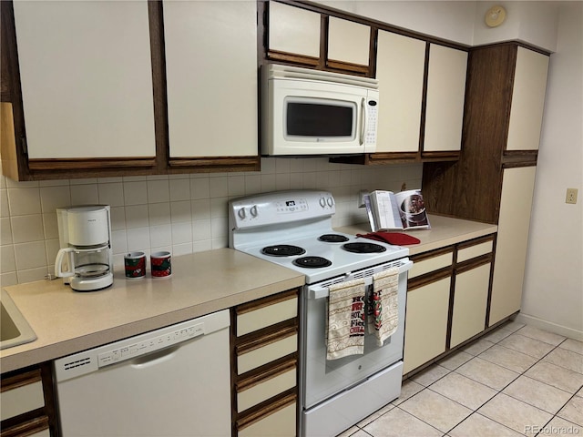 kitchen with white appliances, light tile patterned floors, decorative backsplash, light countertops, and white cabinetry