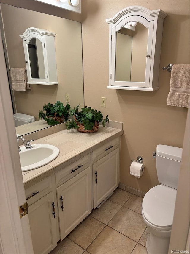 half bathroom with tile patterned flooring, toilet, vanity, and baseboards