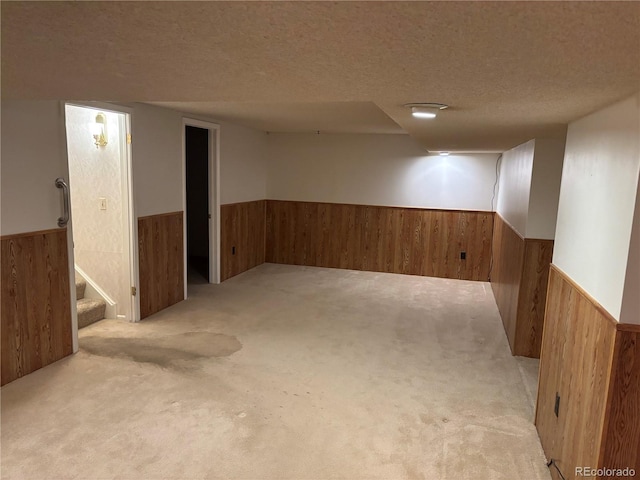 finished below grade area with a textured ceiling, carpet flooring, wood walls, and wainscoting