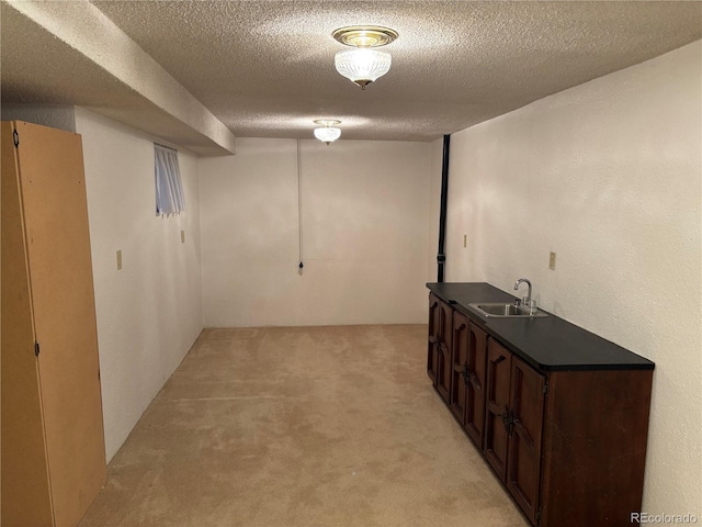 finished basement with light colored carpet, a textured ceiling, and a sink