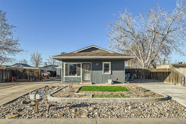 bungalow-style home with fence and concrete driveway