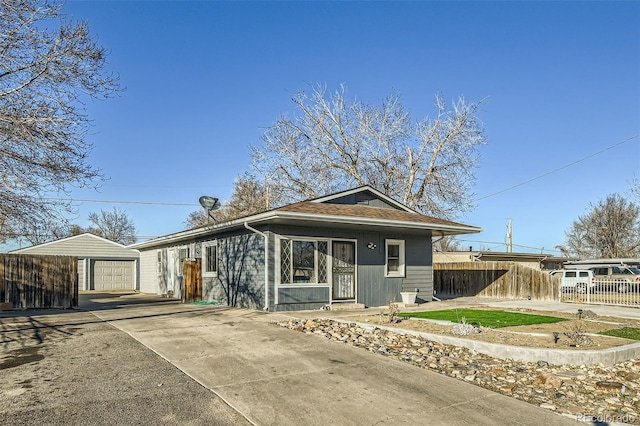 view of front of house with a detached garage, fence, and an outdoor structure