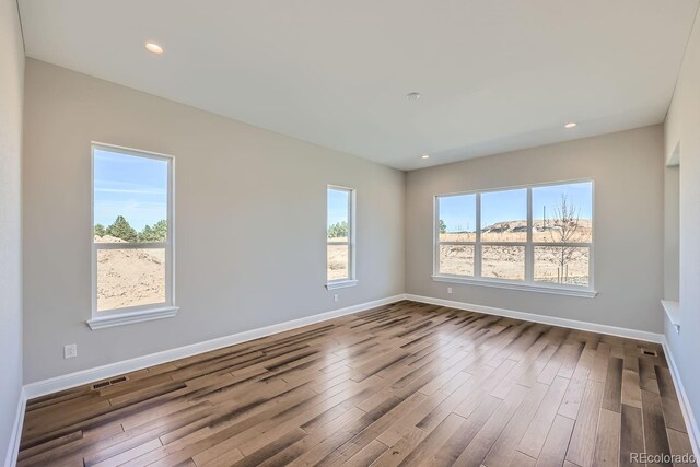 empty room featuring dark wood-type flooring, baseboards, and recessed lighting