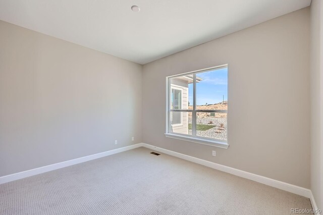 empty room featuring light colored carpet and baseboards
