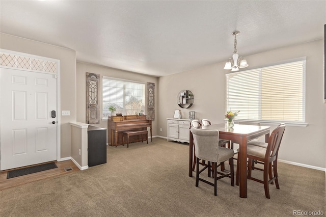 carpeted dining room featuring an inviting chandelier and baseboards