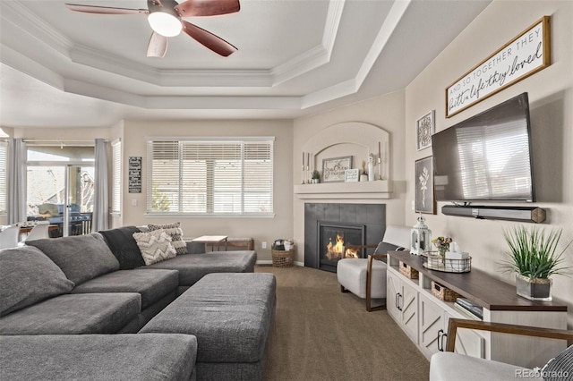 carpeted living room featuring a fireplace, a raised ceiling, and crown molding