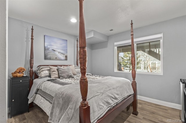 bedroom with wood finished floors, visible vents, and baseboards