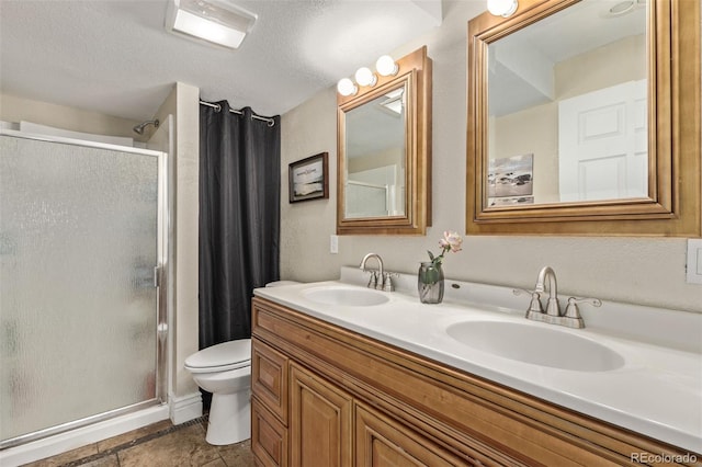 bathroom featuring toilet, a stall shower, double vanity, and a sink