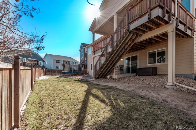 view of yard featuring a deck, a fenced backyard, stairs, a residential view, and a trampoline