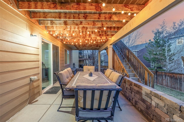 view of patio / terrace featuring stairs, fence, and outdoor dining area