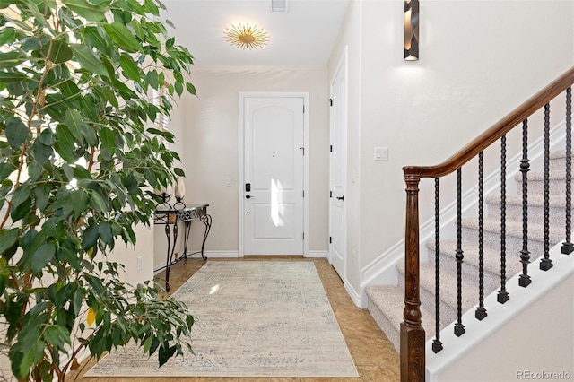 foyer entrance with stairway and baseboards