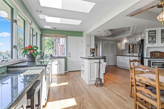 6895 S Norfolk St, Foxfield, CO 80016 - kitchen featuring a skylight, a raised ceiling, light wood finished floors, and white cabinets