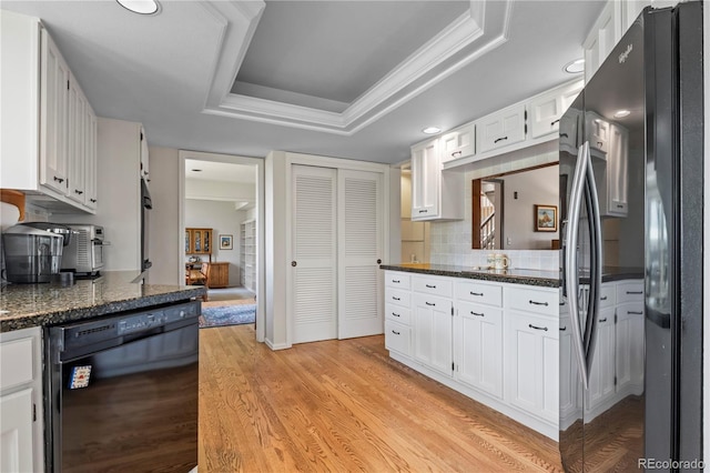 6895 S Norfolk St, Foxfield, CO 80016 - kitchen with freestanding refrigerator, black dishwasher, a raised ceiling, light wood-style floors, and white cabinetry