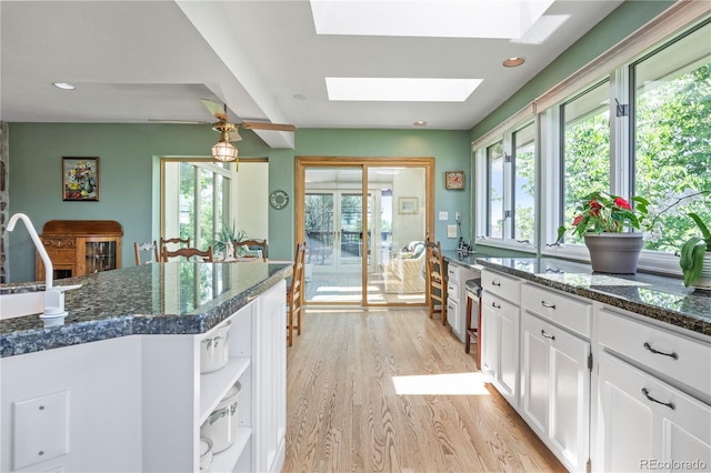 6895 S Norfolk St, Foxfield, CO 80016 - kitchen with light wood finished floors, a skylight, white cabinets, and healthy amount of natural light