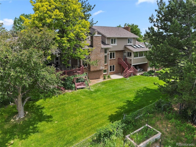 6895 S Norfolk St, Foxfield, CO 80016 - rear view of property featuring a vegetable garden, a lawn, brick siding, and a chimney