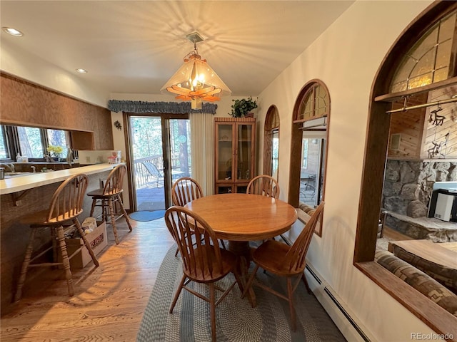 dining room featuring hardwood / wood-style flooring, a healthy amount of sunlight, and baseboard heating