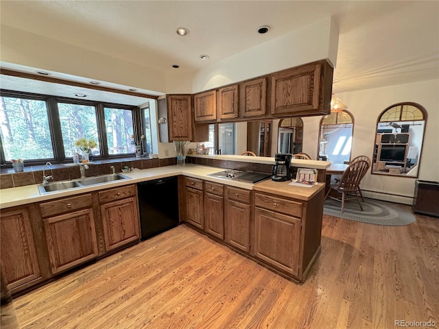 kitchen featuring dishwasher, sink, kitchen peninsula, stainless steel cooktop, and light wood-type flooring