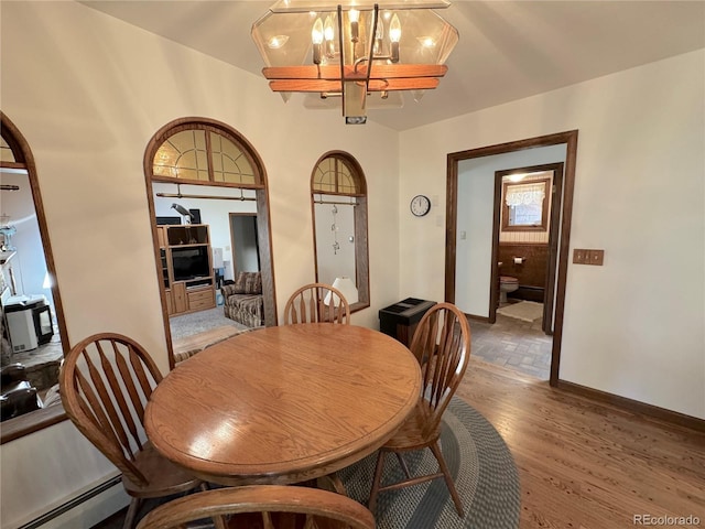 dining room with hardwood / wood-style floors, a baseboard radiator, and a notable chandelier