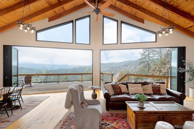 sunroom / solarium with a mountain view, wooden ceiling, lofted ceiling with beams, and ceiling fan with notable chandelier