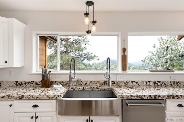 kitchen featuring stainless steel dishwasher, sink, white cabinetry, hanging light fixtures, and light stone countertops