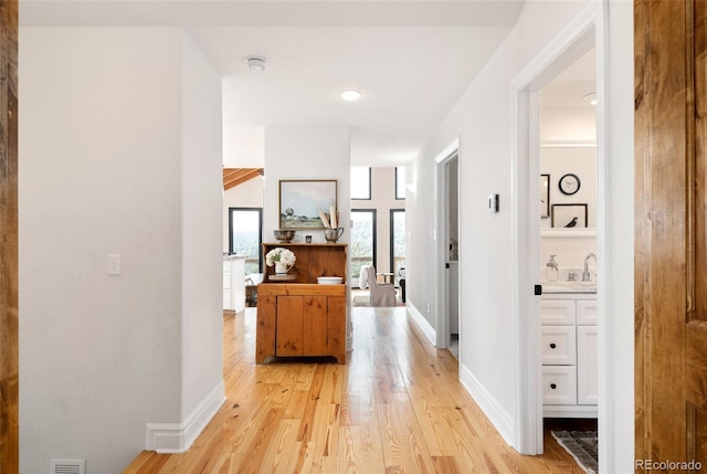 hall with light hardwood / wood-style flooring and sink