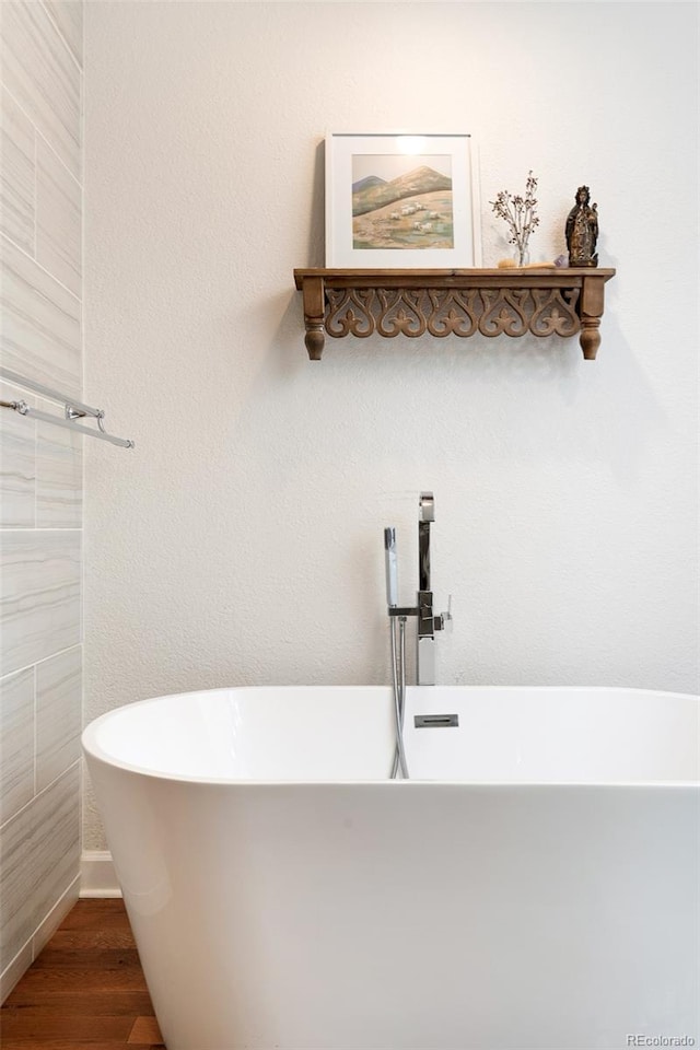 bathroom with a bathing tub and hardwood / wood-style flooring