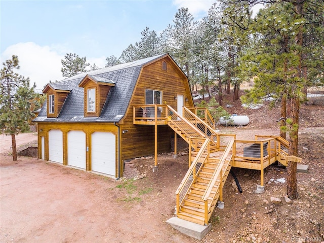 rear view of property featuring a garage and a wooden deck