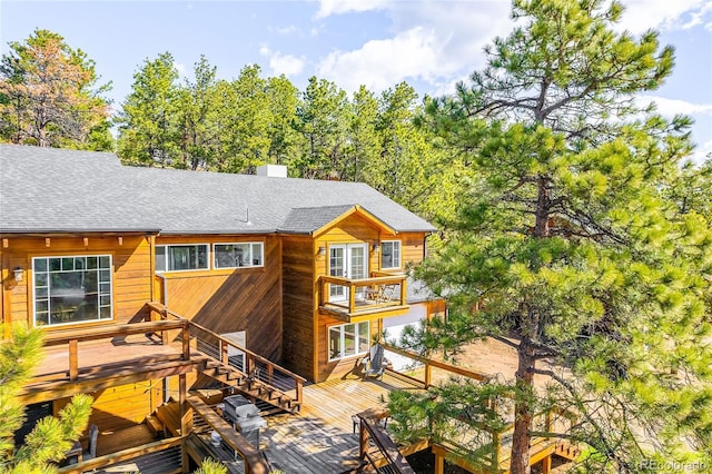 rear view of property featuring a balcony and a wooden deck