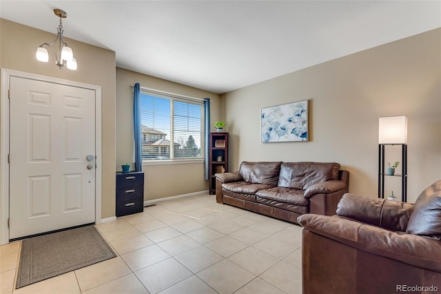 living room featuring light tile patterned floors, baseboards, and a notable chandelier