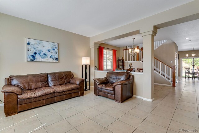 living room featuring light tile patterned floors, baseboards, ornate columns, and a notable chandelier
